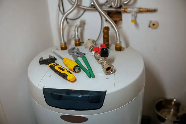 Plumber testing water heater components with diagnostic tools during urgent residential service call