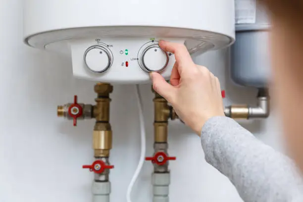 Plumber repairing residential water heater in Summerfield utility room after hot water loss