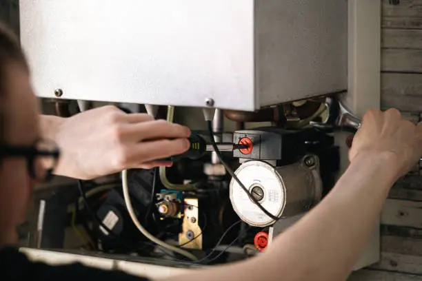 Experienced plumber testing water heater components with meter during detailed repair visit
