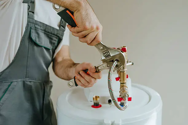 Technician repairing leaking water heater beside laundry area in occupied High Point home